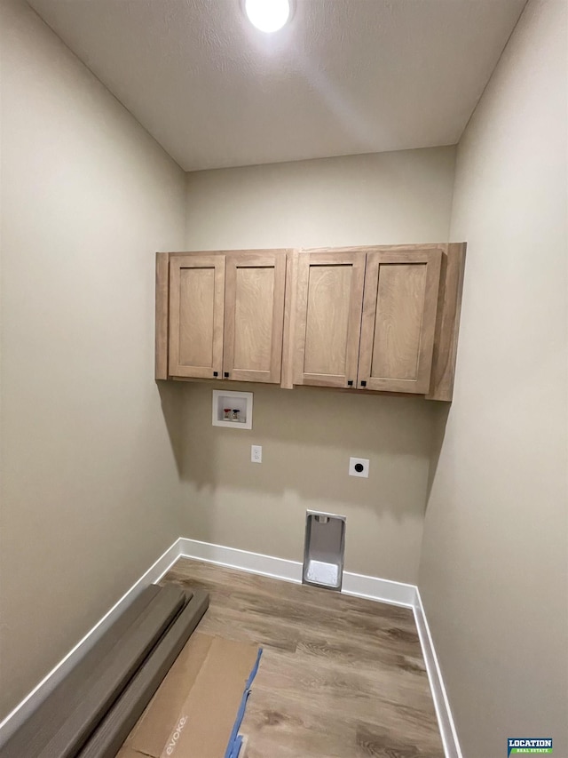 laundry area with cabinet space, baseboards, wood finished floors, hookup for a washing machine, and hookup for an electric dryer