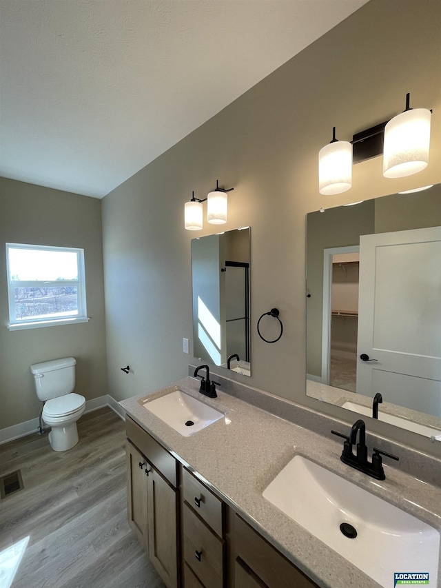 bathroom featuring double vanity, visible vents, a sink, and wood finished floors