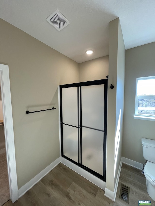 bathroom featuring toilet, a shower stall, and visible vents