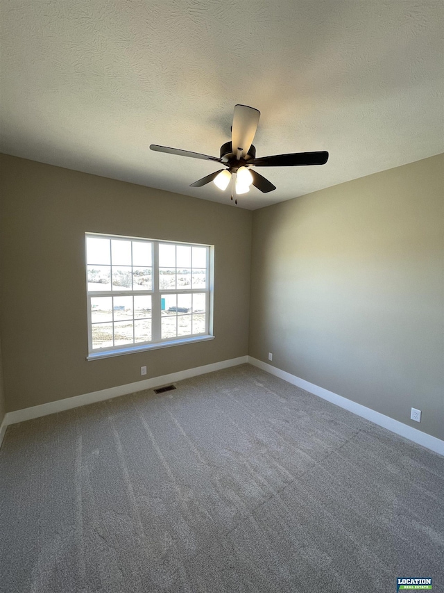 carpeted spare room with a textured ceiling, a ceiling fan, visible vents, and baseboards