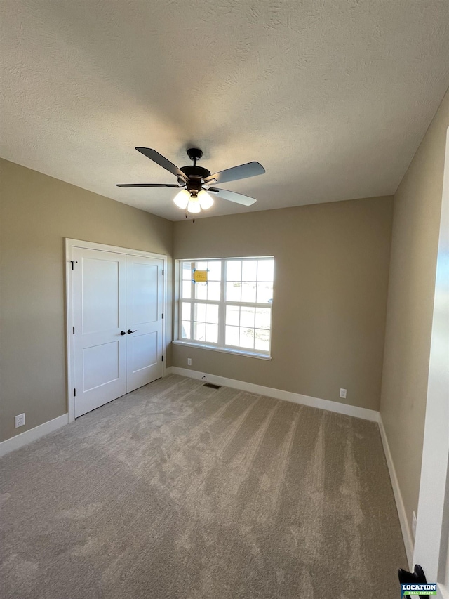 unfurnished bedroom with light carpet, a textured ceiling, and baseboards