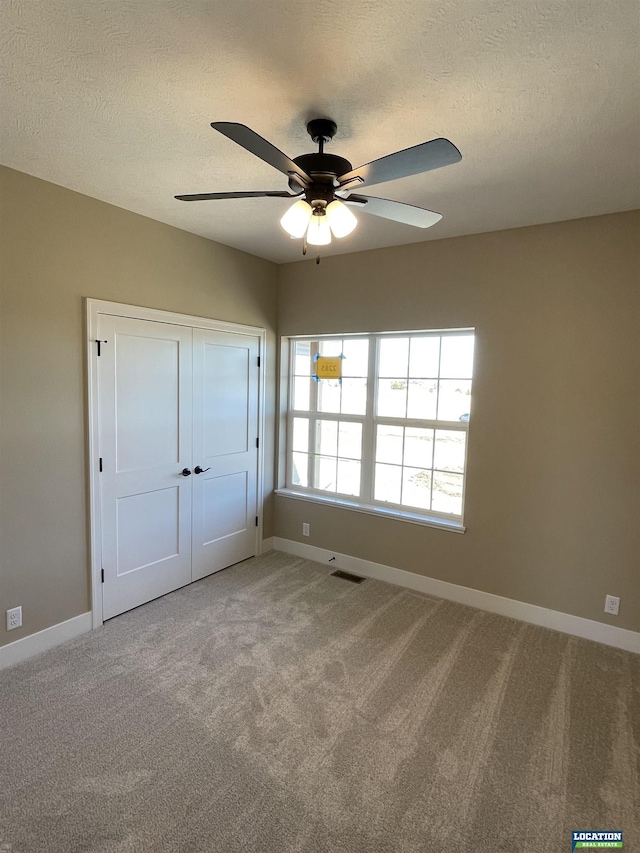 unfurnished bedroom featuring baseboards, visible vents, light carpet, and a textured ceiling