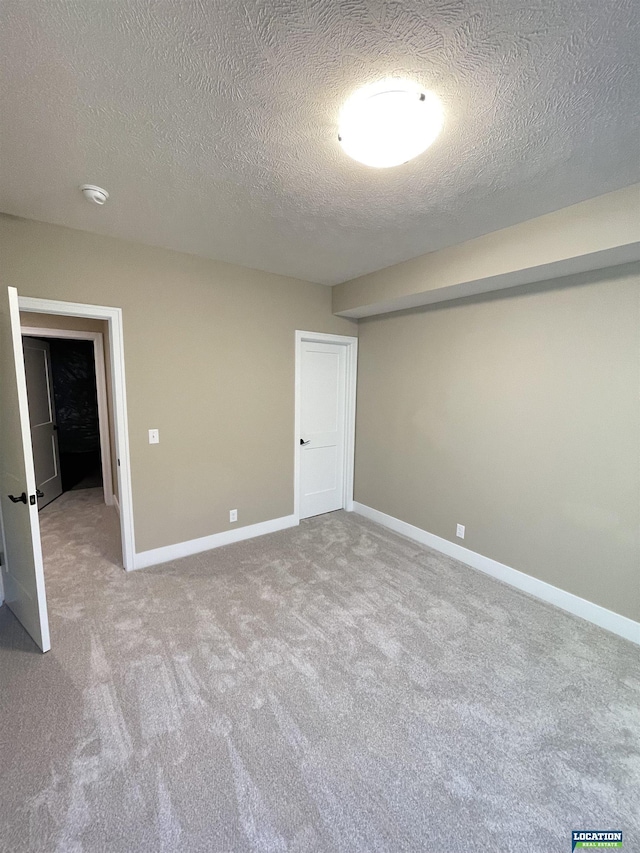 unfurnished bedroom featuring a textured ceiling, carpet flooring, and baseboards