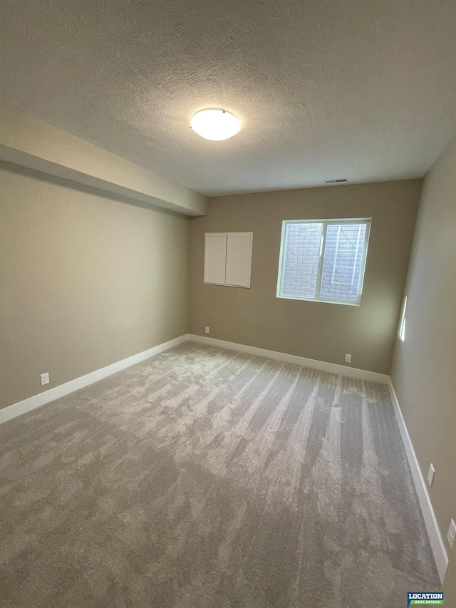 carpeted empty room with a textured ceiling and baseboards