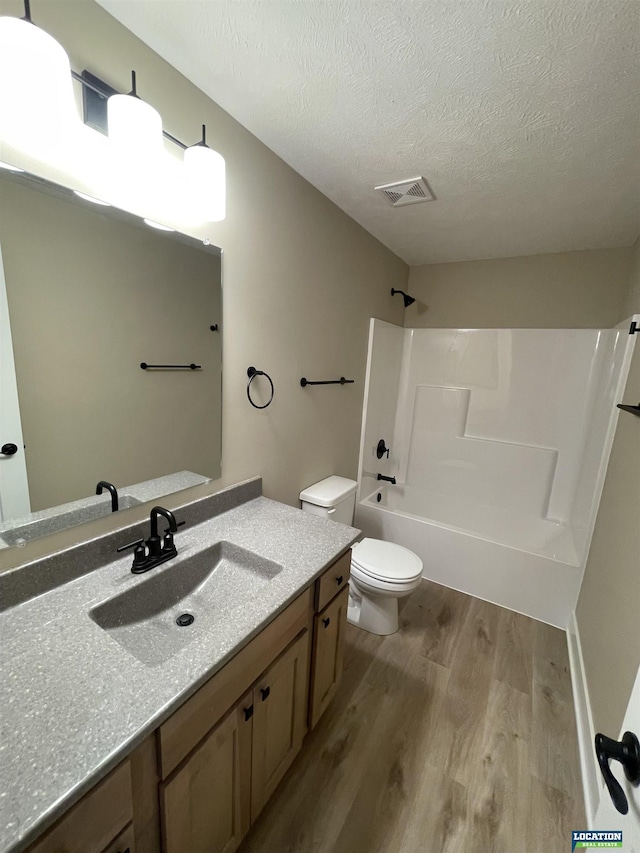 bathroom featuring a textured ceiling, toilet, wood finished floors, bathing tub / shower combination, and visible vents