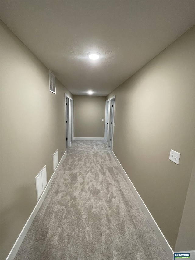 corridor with carpet, baseboards, and visible vents