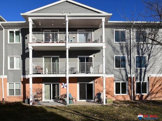 rear view of house featuring central AC unit, a patio, a balcony, and a yard