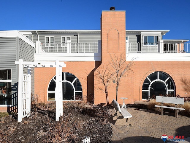 back of house featuring a pergola, a balcony, and a patio