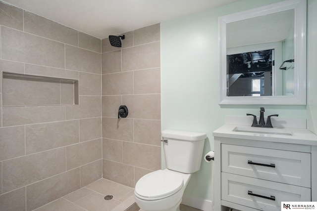 bathroom with vanity, toilet, and a tile shower