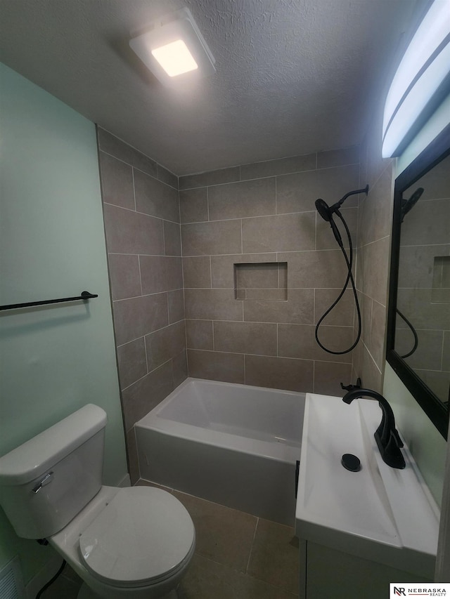 full bathroom with vanity, a textured ceiling, tile patterned floors, toilet, and tiled shower / bath