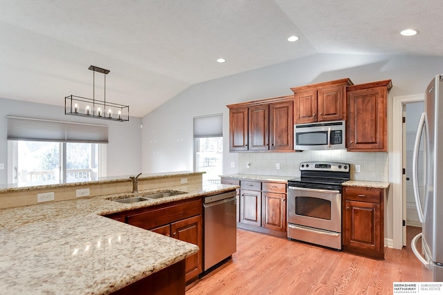 kitchen featuring lofted ceiling, sink, stainless steel appliances, and hanging light fixtures