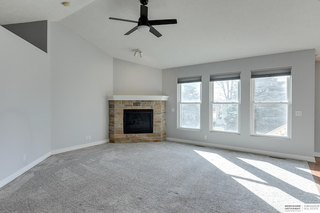 unfurnished living room with a stone fireplace, plenty of natural light, lofted ceiling, and ceiling fan