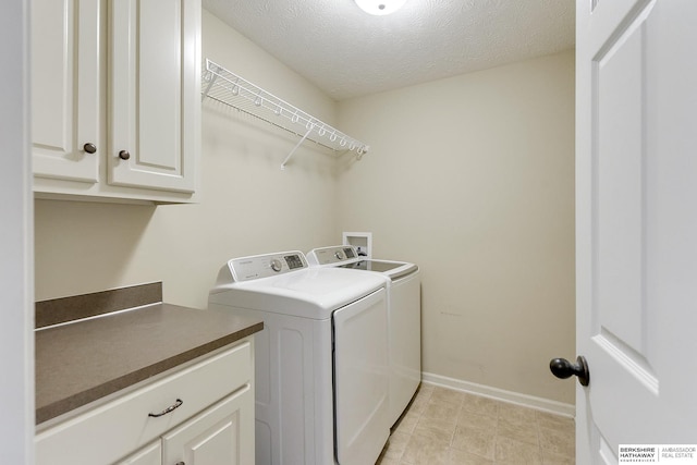 laundry room featuring washer and clothes dryer, cabinets, and a textured ceiling