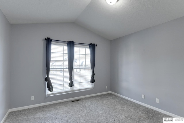 unfurnished room with carpet floors, a textured ceiling, and vaulted ceiling