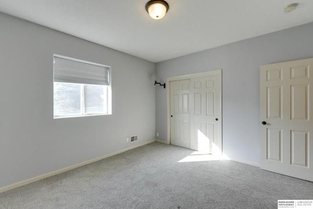 unfurnished bedroom with light colored carpet and a closet