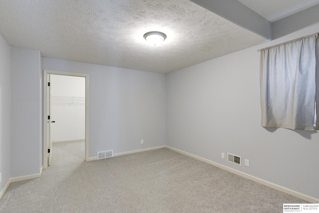 spare room with light colored carpet and a textured ceiling