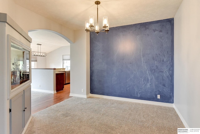 carpeted spare room featuring lofted ceiling and a notable chandelier