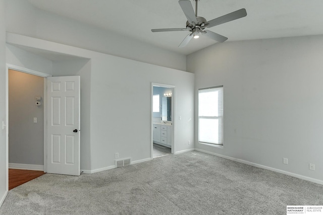 unfurnished bedroom featuring light carpet, lofted ceiling, ceiling fan, and ensuite bathroom