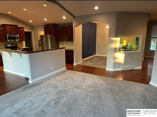 kitchen featuring stainless steel appliances, dark colored carpet, and a breakfast bar area