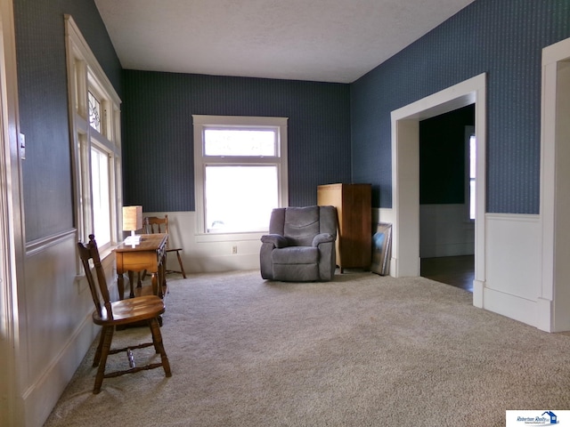 living area with carpet flooring, wallpapered walls, and a wainscoted wall