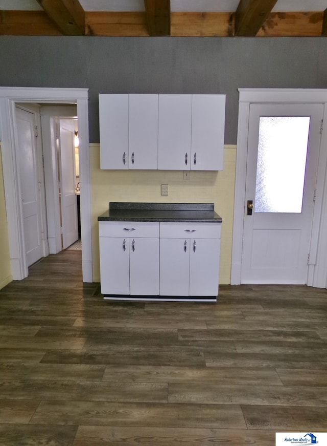 kitchen with beamed ceiling, dark countertops, dark wood finished floors, and white cabinets