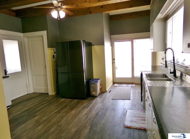 kitchen with beam ceiling, dark wood-style flooring, freestanding refrigerator, a sink, and stainless steel counters