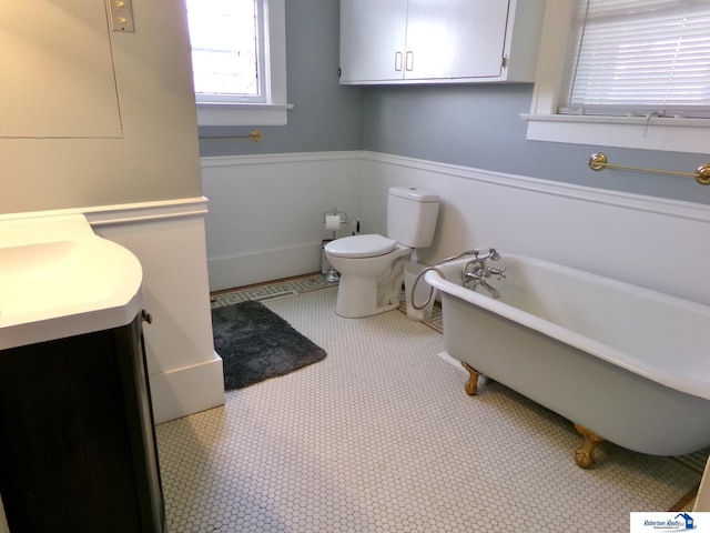 full bath with a freestanding tub, vanity, wainscoting, and toilet