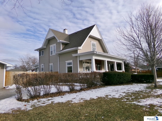 view of snow covered exterior with a chimney and fence