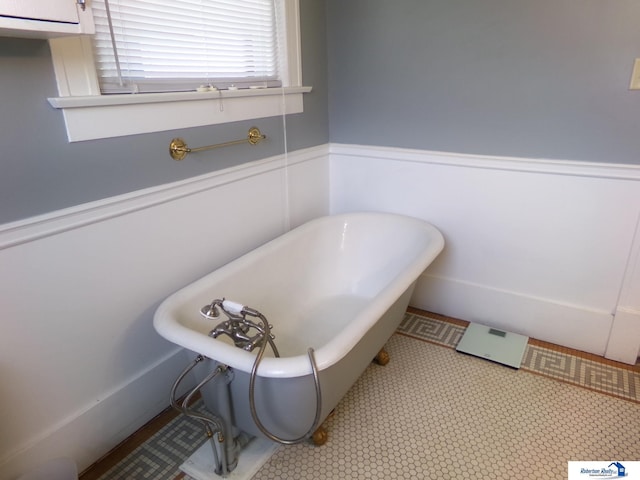 bathroom with a wainscoted wall and a freestanding bath