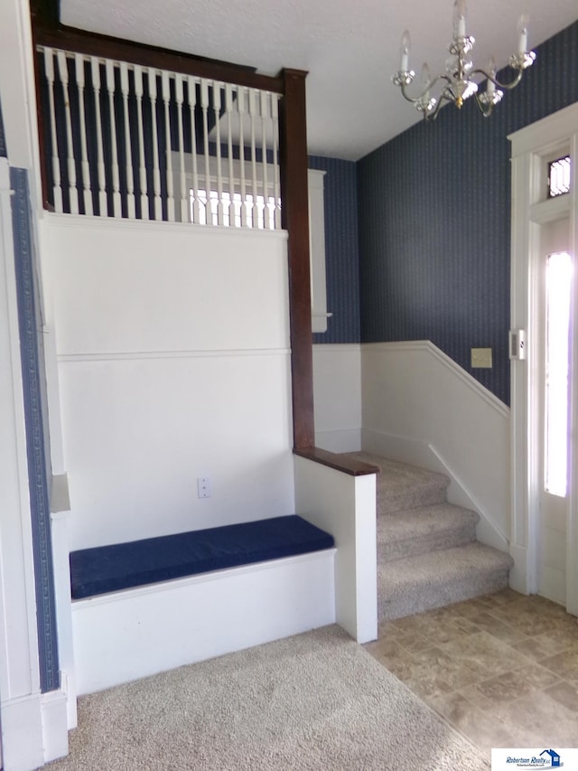 stairway featuring a notable chandelier, wallpapered walls, and carpet floors