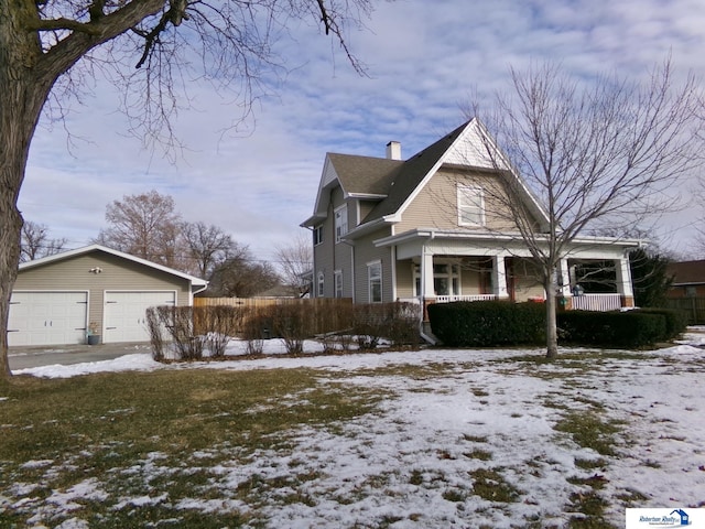 view of front of home with a garage, an outbuilding, a porch, and a chimney