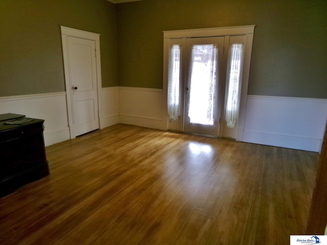 entrance foyer with a wainscoted wall and wood finished floors