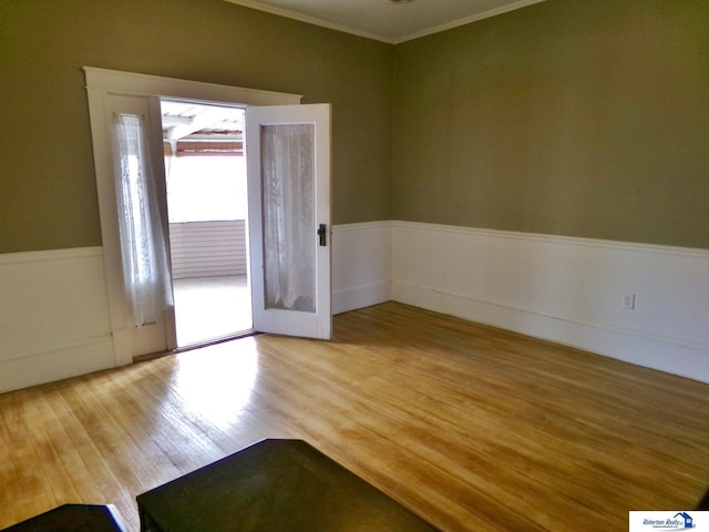 interior space with wood finished floors, a wainscoted wall, and ornamental molding