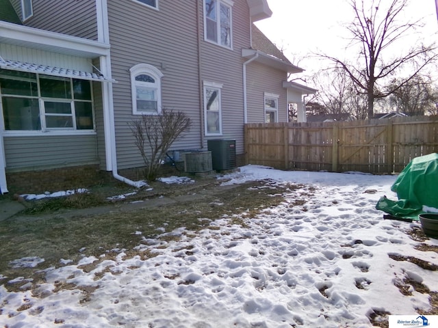 yard covered in snow with central air condition unit and fence