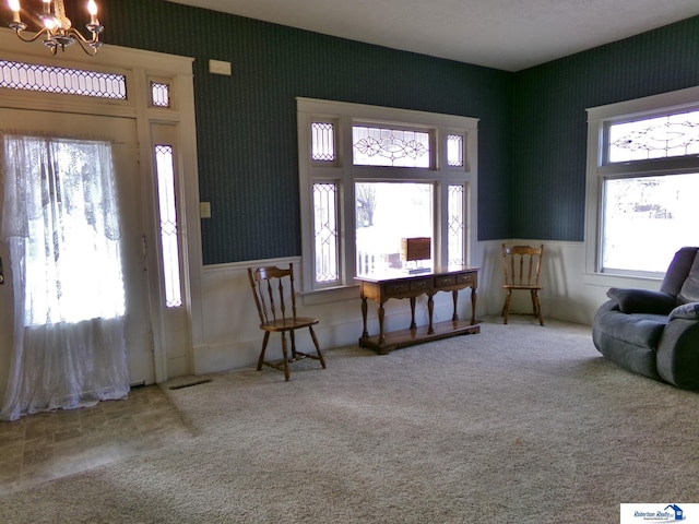 carpeted foyer with wallpapered walls and an inviting chandelier