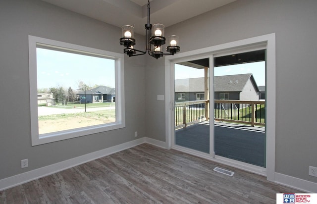 unfurnished dining area featuring hardwood / wood-style floors and an inviting chandelier