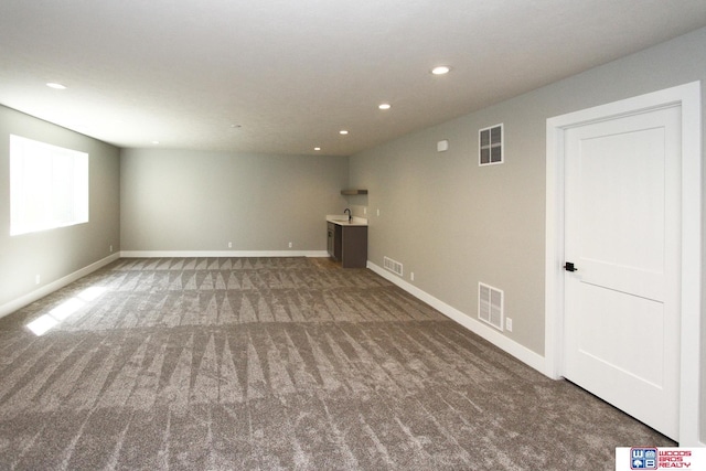 unfurnished living room featuring carpet flooring and sink