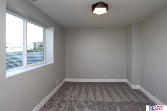 empty room featuring a healthy amount of sunlight and dark colored carpet