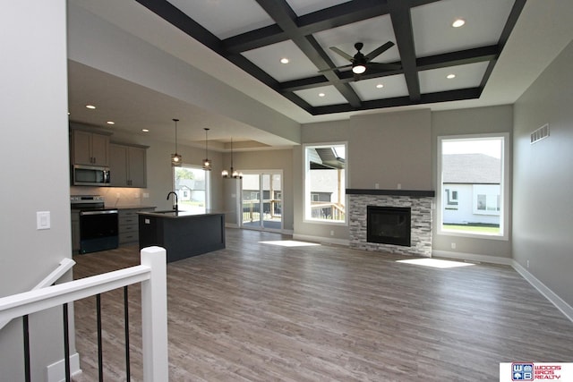 unfurnished living room with a fireplace, sink, hardwood / wood-style flooring, beam ceiling, and coffered ceiling