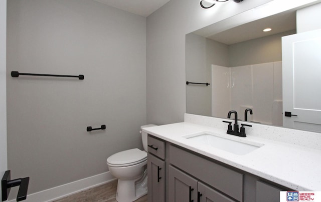 bathroom with toilet, vanity, wood-type flooring, and a shower