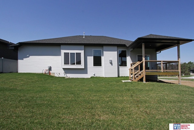 rear view of property with a wooden deck and a lawn