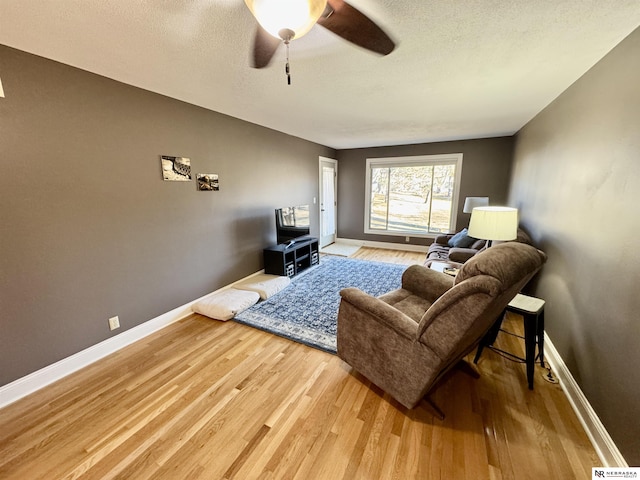 living room featuring ceiling fan, a textured ceiling, and hardwood / wood-style flooring