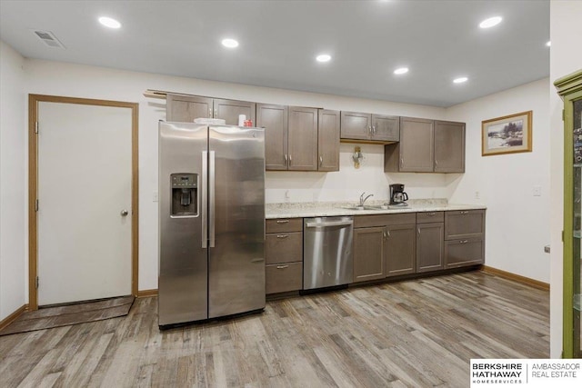 kitchen featuring stainless steel appliances, sink, and light wood-type flooring