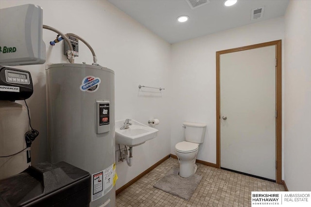 bathroom featuring toilet, sink, and water heater