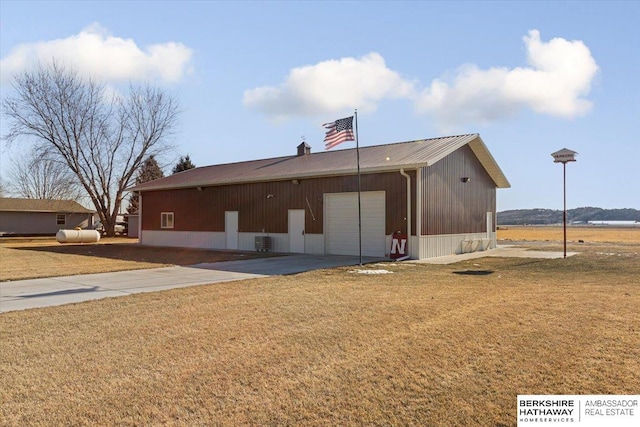 rear view of property featuring a garage, cooling unit, and a lawn