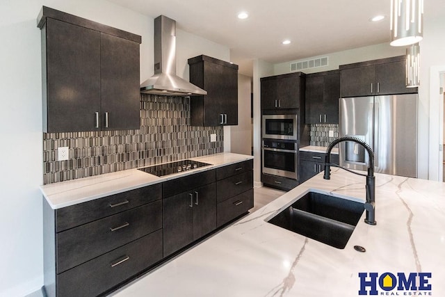 kitchen with decorative light fixtures, wall chimney range hood, decorative backsplash, sink, and stainless steel appliances