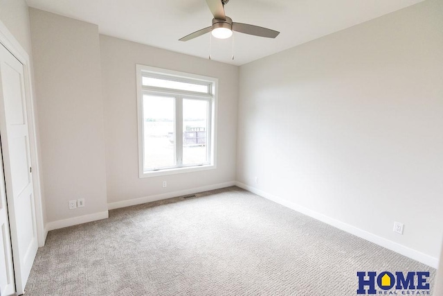 carpeted spare room featuring ceiling fan