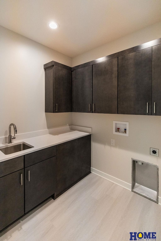 washroom with electric dryer hookup, light wood-type flooring, washer hookup, cabinets, and sink