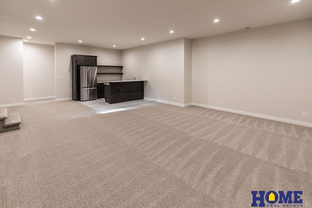 unfurnished living room featuring light colored carpet and bar