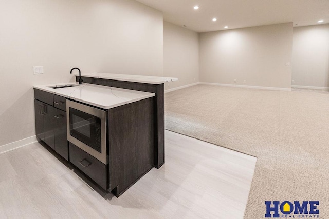 kitchen with stainless steel microwave, light carpet, and sink